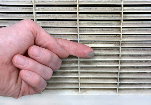 A hand swipes dust off of a heating and cooling vent.